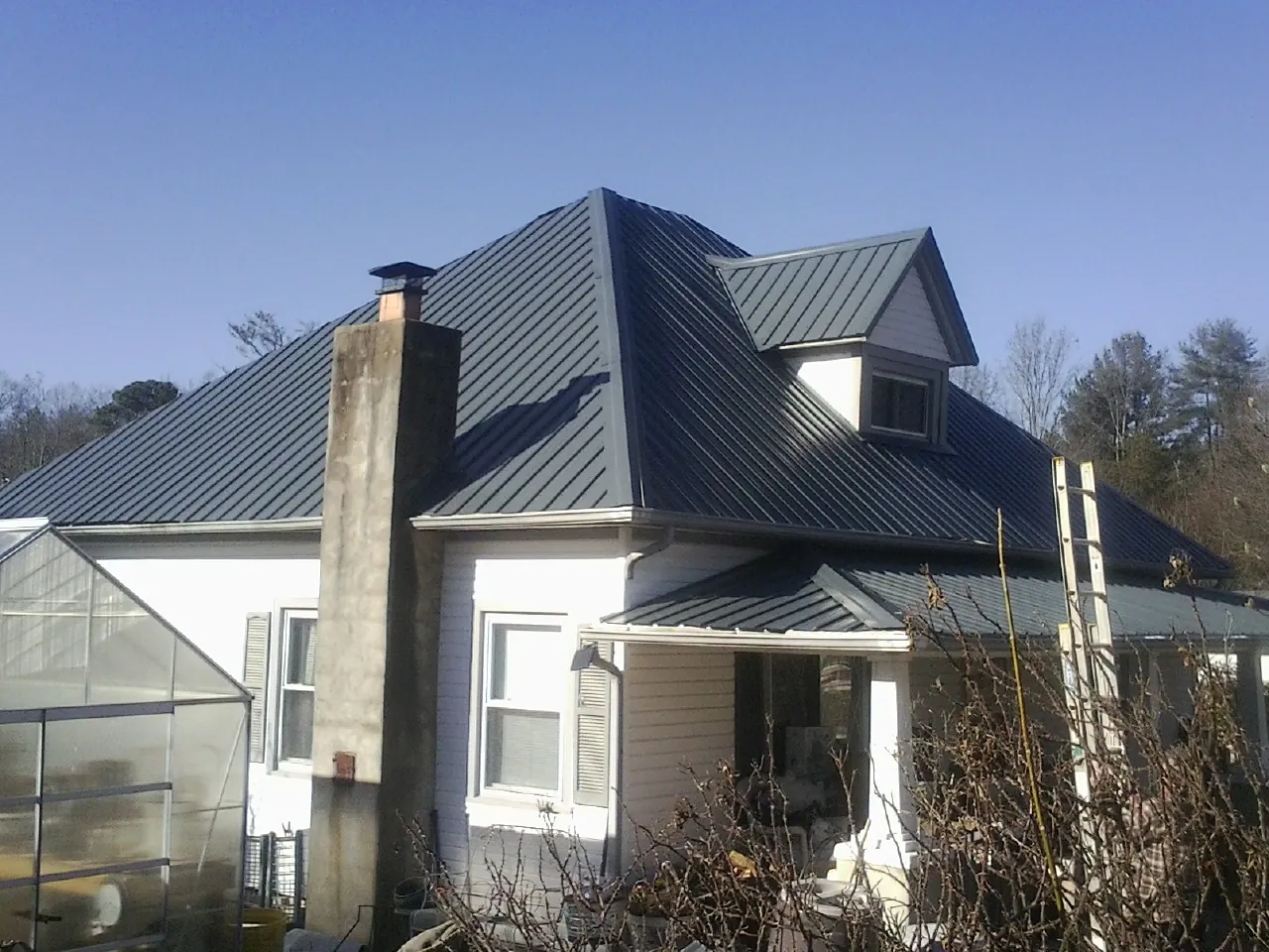 Dark blue standing seam metal roof on a white farmhouse with dormer — Slate & Tile Roof Repair by Roofing Brothers in Zelienople