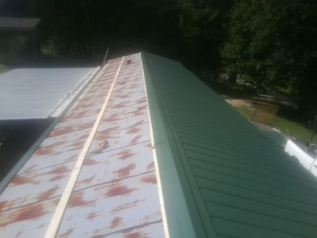 Old rusted panels beside newly installed green metal roofing — Wind Damage Roof Repair by Roofing Brothers in Zelienople