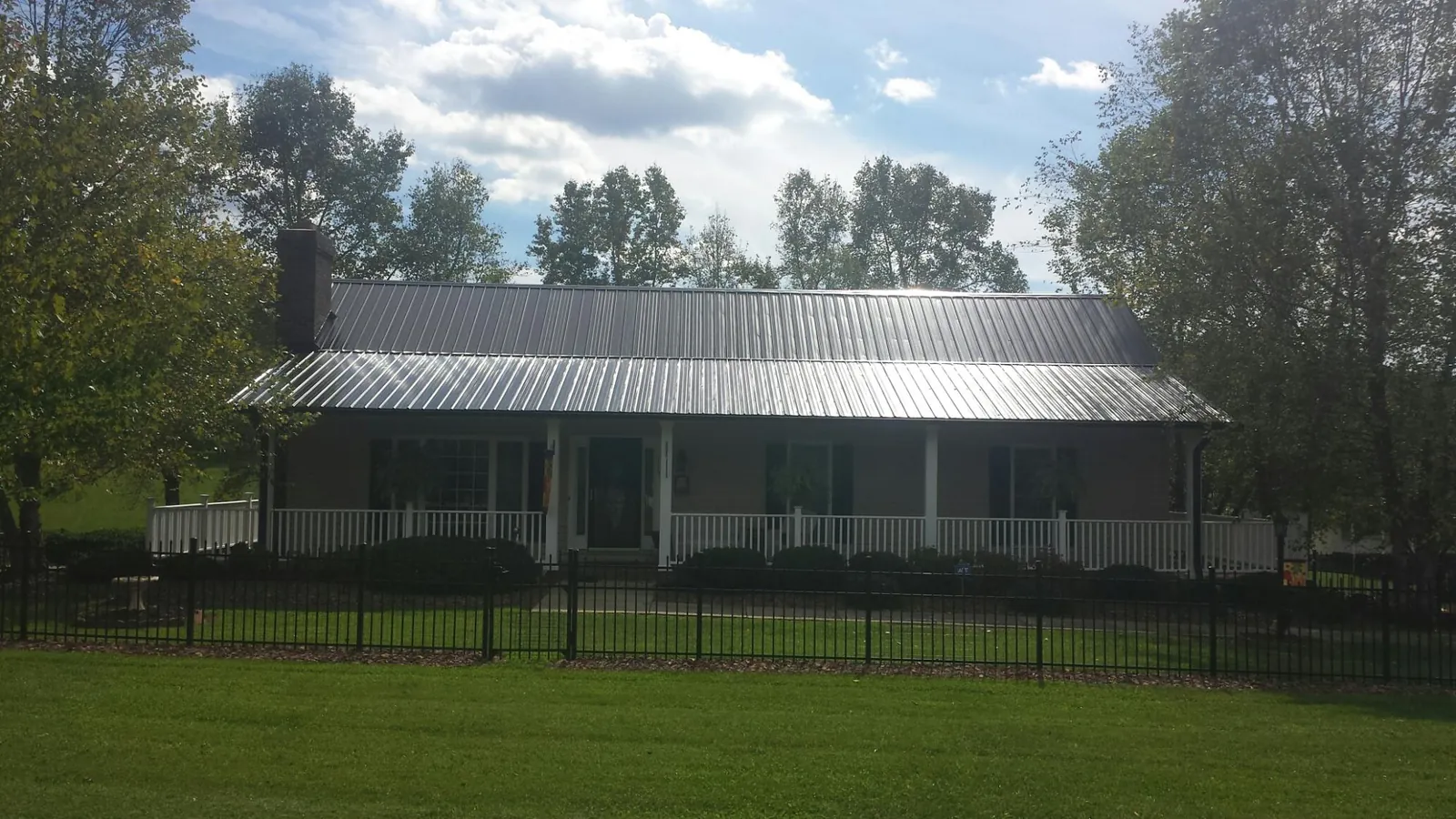 Gray metal roof on a brick ranch with a full width front porch — Gutter Guard Installation work by our crew in Zelienople
