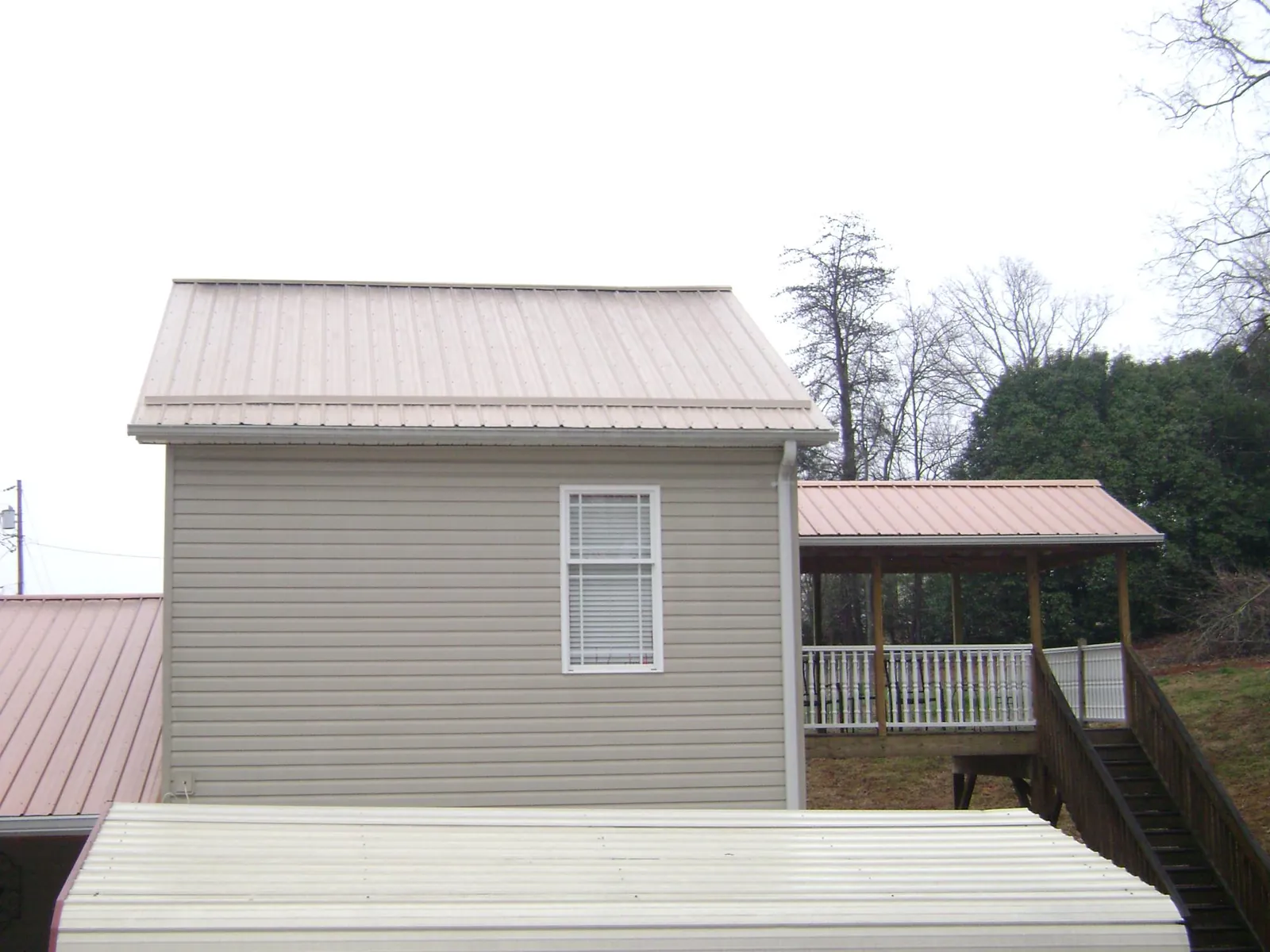 Tan metal roofs on a two story addition and attached porch, from a Roof Replacement job in Zelienople