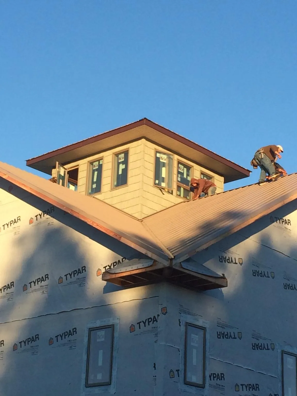 Roofers working around a rooftop cupola on a new metal roof at sunset — Roof Waterproofing in Zelienople by Roofing Brothers